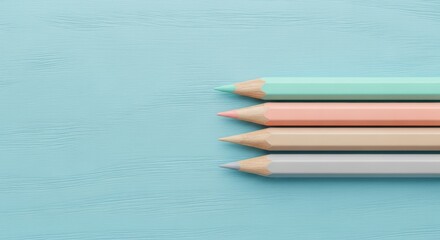 Obraz premium Photo of four pastel colored pencils are neatly arranged on a light blue wooden surface