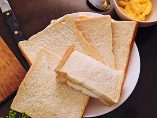 Fresh Sliced Bread on White Plate with Butter and Knife Dark Background.