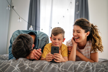 Happy family and kid having fun with smartphone, digital gadget at home. People, technology