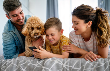 Happy family and kid having fun with smartphone, digital gadget at home. People, technology