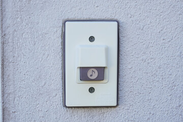 Close-up of a doorbell mounted on a textured, light-colored wall.