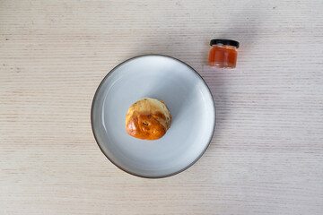 A plate of fresh scone and a small jar of jam.
