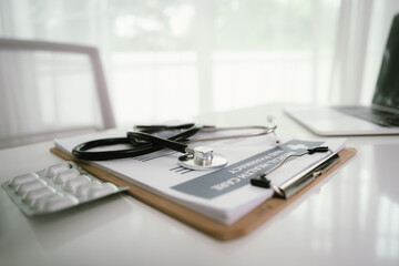 A doctor in a white coat uses a smartphone at a desk with a stethoscope, pills, medical documents, and a pen, focusing on healthcare communication and patient care.