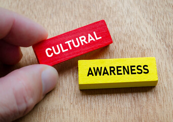 Cultural Awareness shown by hand holding red and yellow wooden blocks. Diversity and inclusion concept