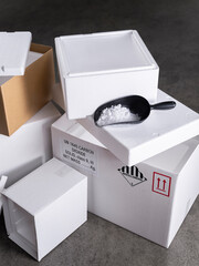 White shipping boxes with UN1845 carbon dioxide labels and black scoop filled with dry ice