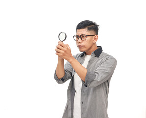 Focused young man inspecting with magnifying glass on white background for investigation