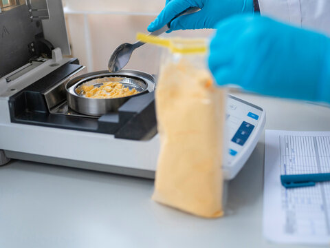 Food scientist conducting weight analysis of yellow substance using electronic laboratory balance