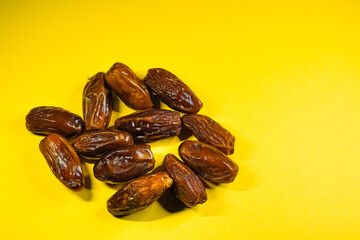 Dried dates arranged in a circle on a bright yellow background.