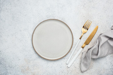 Empty plate, cutlery and table cloth. Table setting on grey concete background, top view, copy...