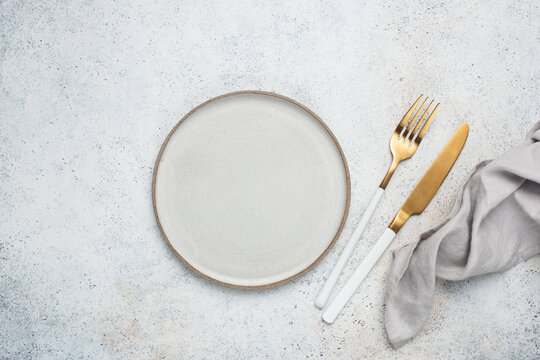 Empty plate, cutlery and table cloth. Table setting on grey concete background, top view, copy space for design or text elements