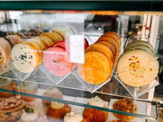 Colorful macarons displayed in a pastry shop cabinet during a sunny afternoon
