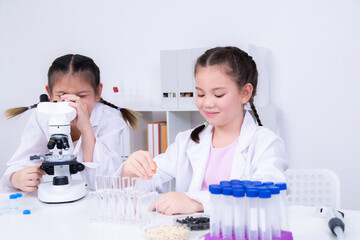 Learning and education for student in classroom, children focus on pipette handling and microscope...