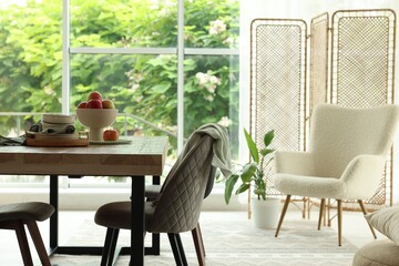 Wooden table, chairs, armchair and decor in dining room. Interior design
