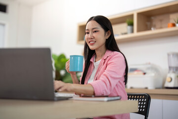 Working from Home: Young Woman Typing on Laptop with Coffee in Hand