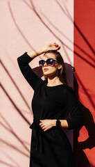 Fashionable Woman Posing Against Pink Wall in Sunlight