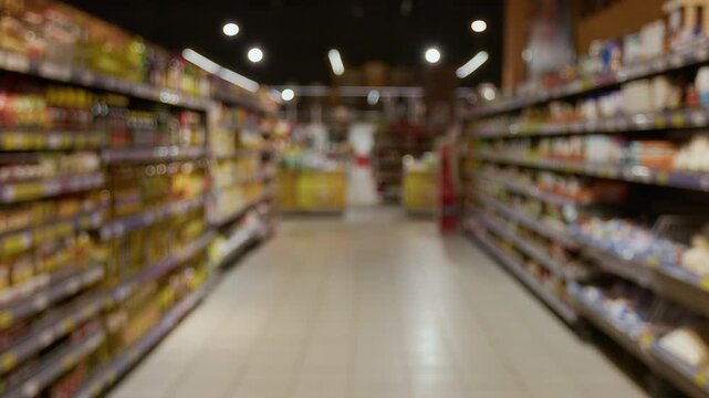 No people view of grocery store aisle with shelves stocked with various products, captured with blurred focus creating indistinct background
