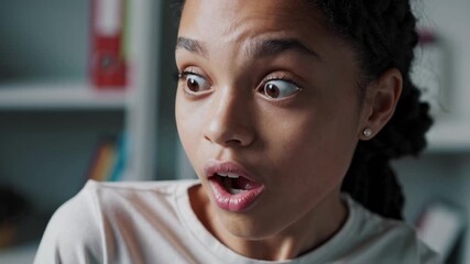 Young female student with braided hair showing wide eyed, open mouthed surprise in classroom setting near bookshelves - Powered by Adobe
