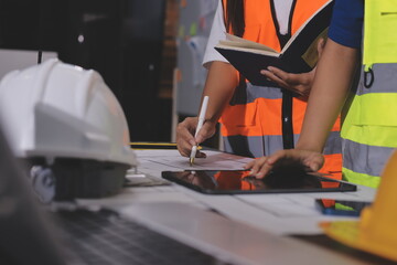 Obraz premium Closeup of team of industrial engineers meeting analyze machinery blueprints consult project on table in manufacturing factory. Working in manufacturing plant or production plant.
