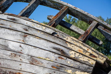 Weathered wooden boat bow showcases intricate details against a clear blue sky in a scenic outdoor location