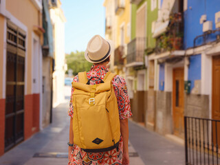 Woman in dress strolls through colorful streets of Spanish coastal town of La Vila Joiosa or Villajoyosa. sunny winter atmosphere highlights charm of Mediterranean architecture and quiet seaside life