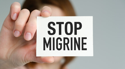 A person holding a white card that says Stop Migraine