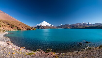 turquoise waters of lake caviahue under rocky landscape and snowcapped copahue volcano caviahue neuquen argentina