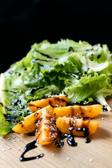 Sliced tomatoes drizzled with sauce and sprinkled with sesame seeds on a wooden cutting board. Close-up of tomatoes and lettuce. Concept of healthy eating and organic farm products