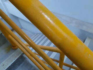 Detailed texture of an old yellow stair railing with worn paint, perfect for industrial, construction, or public safety visual content