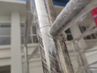 Wrapped stainless steel railing during construction phase, with building facade in the background,...