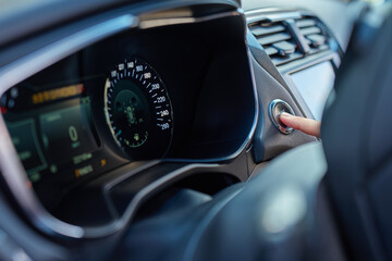 Close-up of hand pressing start button to turn on car engine. Keyless ignition system in modern car