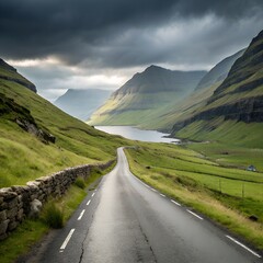 Scenic winding road through a lush green valley towards a tranquil lake under dramatic stormy skies