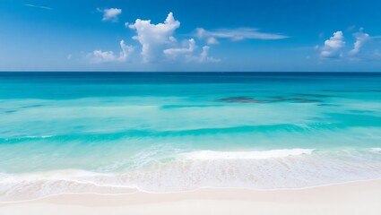 Obraz premium Serene turquoise ocean waves gently lap onto a pristine white sand beach under a blue sky