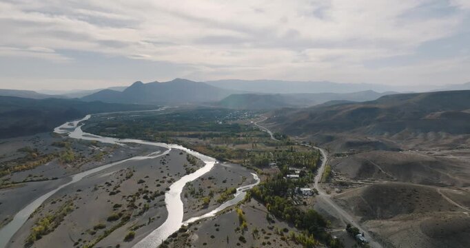 Aerial panoramic view of Neuquen river in Chos Malal through arid land and highway. Patagonia Argentina