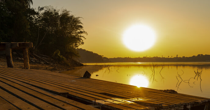 Beautiful sunrise over a small wooden pier and gallons, golden and clear sky, with fog on the freshwater beach of the V&aacute;rzea das Flores dam, in Contagem, Minas Gerais, Brazil.