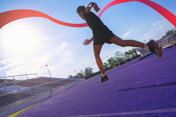 Fit young man running sprinting to red finish line at the racetrack. Finisher, marathon runner sprinting moment at the racetrack.