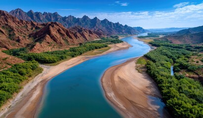 The winding Yellow River flows through the vast desert, with mountains in the background and a clear blue sky