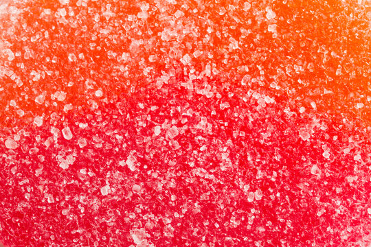 High-detail macro view showcasing sweet sugar granules sprinkled over red‑orange candy, highlighting vivid color contrast and dessert appeal in a bright background. Photo