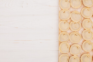 Raw dumplings with meat filling resting on wooden board