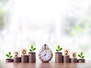 Vintage watch, Wooden blocks with the number 2026 and plants growing up on stack of coins. The concept of saving money for manage time to success business in year 2026