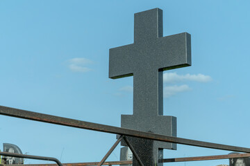Marble cross in a serene cemetery. In the embrace of nature a granite cross stands as a testament...