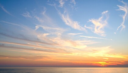 Obraz premium Soft pastel sunset sky with wispy clouds, casting a warm glow over a calm horizon, ultra-crisp