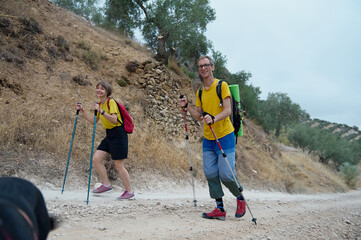 Happy Couple Hiking in Scenic Mountain Trail with Trekking Poles