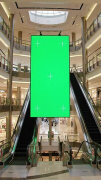 Green screen display in a modern shopping mall with escalators and open space
