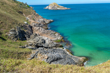 Top view of Praia Grande, with beautiful blue sky, rocks, mountains with low vegetation and sea with crystal clear green waters and small islands. Rio de Janeiro, Brazil.