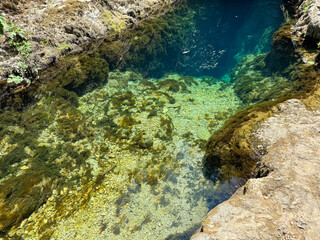 Natural karst spring with transparent turquoise water and underwater rocks in Sardinia