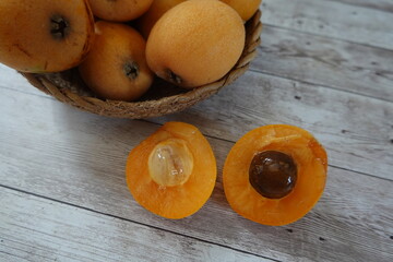 Fresh loquats showing seed and flesh on wooden table