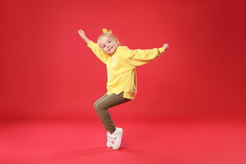 Cute little girl dancing on red background