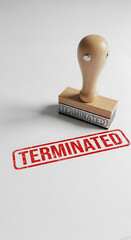 Wooden stamp with the word terminated imprinted on white background indicating job loss