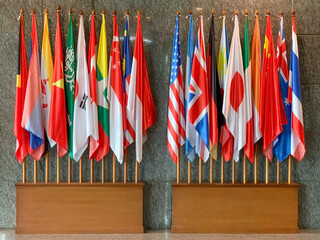 Multiple national flags representing international cooperation and diplomacy displayed indoors. © aryamhrdk16