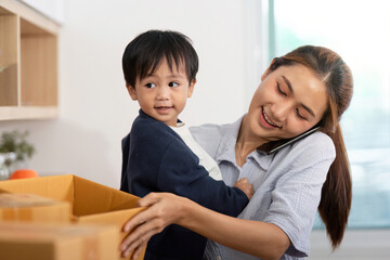 Sell Online: Mother holding child while managing packages on phone